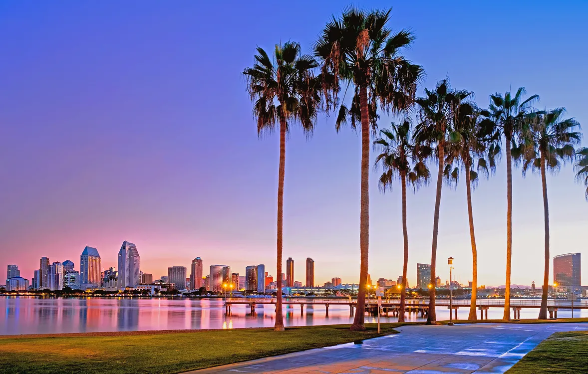 San Diego skyline and palm trees at sunset across the bay - Los Angeles to San Diego long-distance car service